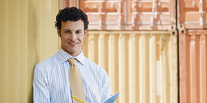 Portrait d'un homme d'affaires adulte moyen appuyé sur un conteneur de cargaison et regardant la caméra.Forma horizontale, vista frontale, spaziu di copia